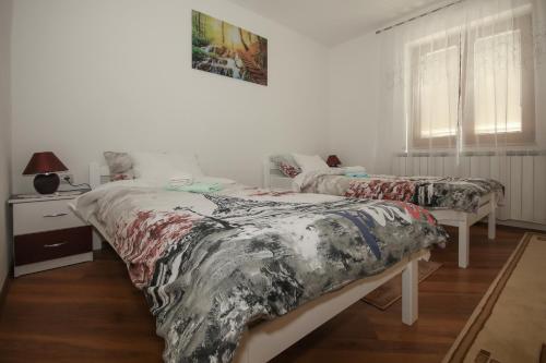 ein Schlafzimmer mit zwei Betten und einem Tisch und einem Fenster in der Unterkunft Apartman Lucija & Luka in Otočac