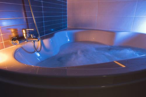 a bath tub filled with blue water in a bathroom at Albergue GBC Hostel in Pontevedra