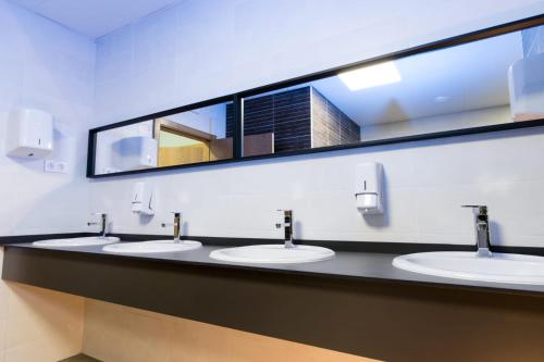 a bathroom with two sinks and two mirrors at Albergue GBC Hostel in Pontevedra