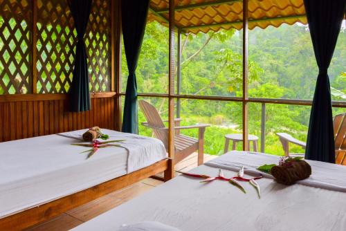 two beds in a room with a window at Pacuare River Lodge in Bajo Tigre