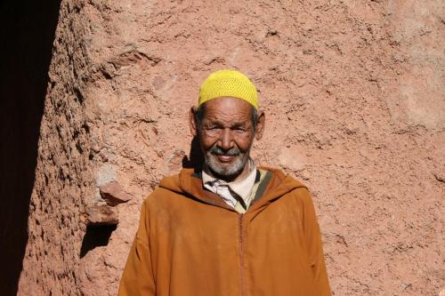 a man wearing a yellow hat standing in front of a wall at Kasbah Africa - High Atlas Dark Sky & Nature Lodge in Ouirgane