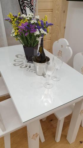 a white table with wine glasses and flowers on it at Villa Fortuna - Regionalne apartamenty & SPA - Sauna, Grill, Jacuzzi z widokiem na Tatry in Zakopane
