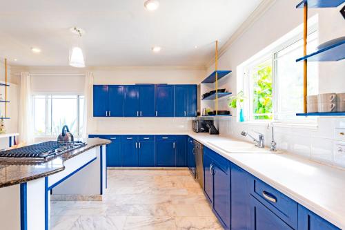 una cocina azul con encimeras blancas y armarios azules en Villa Northwinds - At Orange Hill - Private Pool, en Nassau