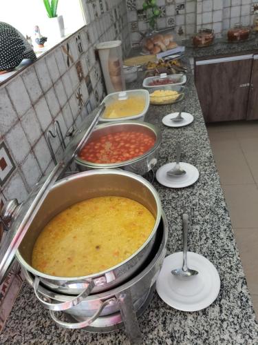 a kitchen counter with several pans of food on it at Porto De Galinhas Pousada Raízes Do Porto in Porto De Galinhas
