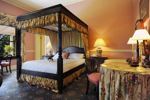 a bedroom with a four poster canopy bed and a table at Chateau Yering in Yarra Glen