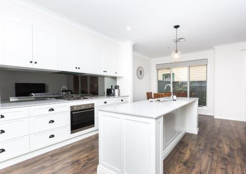 a kitchen with white cabinets and a white counter top at Glen’s Inner City Escape - CBD Central in Wagga Wagga