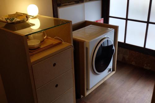 a washer and dryer in a room with a dresser at 宿一灯 Guest House HITOTOMORI in Mitsugarasuchō