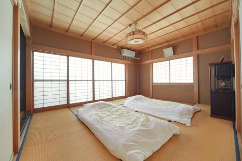 2 Betten in einem großen Zimmer mit Fenstern in der Unterkunft Kouya in Takayama