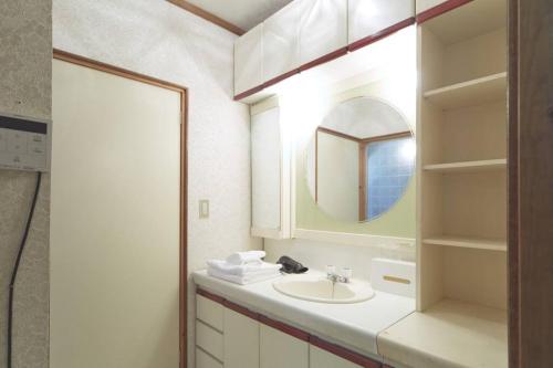ein weißes Badezimmer mit einem Waschbecken und einem Spiegel in der Unterkunft Kouya in Takayama