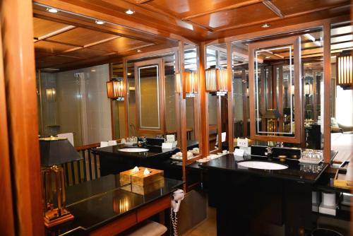 a bathroom with two sinks and two mirrors at Rama Gardens Hotel Bangkok in Bangkok