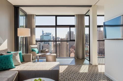 a living room with a couch and a large window at Fraser Suites Sydney in Sydney