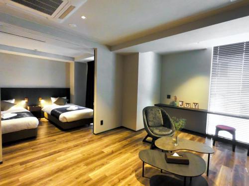 a hotel room with two beds and a chair at Hotel S-Presso South in Osaka