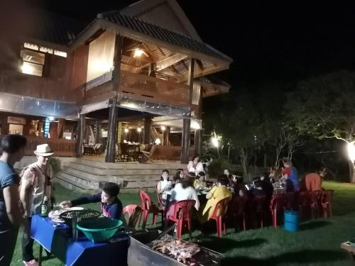 a group of people sitting outside of a building at night at Ruen Thai Rim Haad in Klaeng