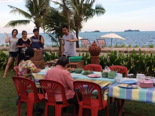 a group of people sitting around a table by the ocean at Ruen Thai Rim Haad in Klaeng