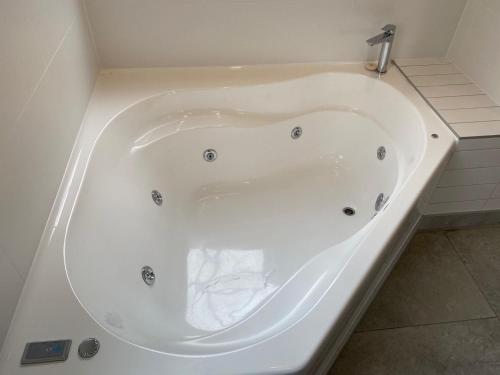 a large white bath tub in a bathroom at Southern Comfort Motel in Christchurch