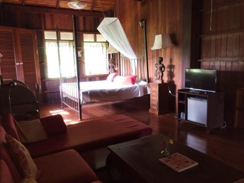 a bedroom with a bed and a tv in a room at Ruen Thai Rim Haad in Klaeng