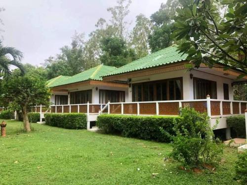 a house with a green roof and a yard at Ruen Thai Rim Haad in Klaeng