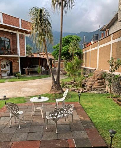 a patio with chairs and a table and a palm tree at La Buena Suerte in Tepoztlán