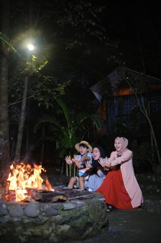 a group of people sitting around a fire at night at Hau Eco Lodges Citumang Pangandaran in Pangandaran