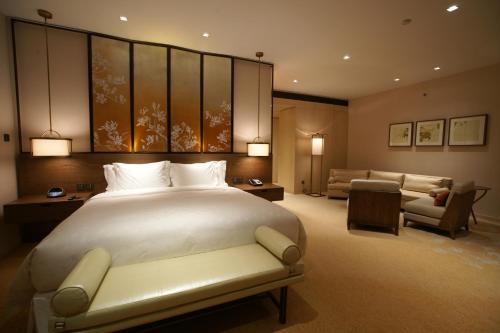 a bedroom with a large bed and a living room at HUALUXE Shanghai Twelve At Hengshan, an IHG Hotel in Shanghai
