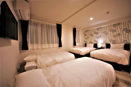 小樽市にあるCozy Inn OTARUのベッド3台とテレビが備わるホテルルームです。
