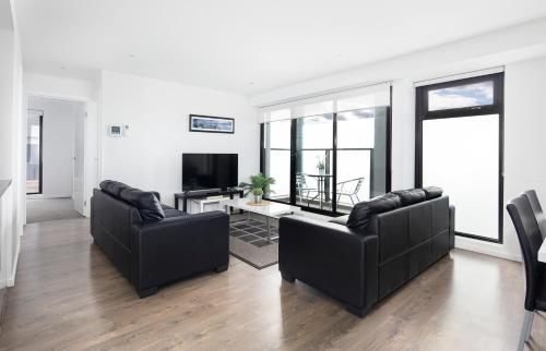 a living room with two couches and a tv at RNR Serviced Apartments North Melbourne in Melbourne