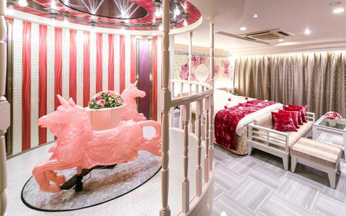 ein Schlafzimmer mit einem rosa Bett und einem Kinderbett in der Unterkunft Hotel Regent (Adult Only) in Nagoya