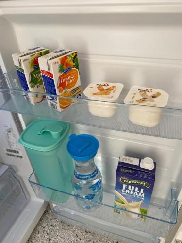 an open refrigerator with milk and yogurt and a bottle of water at Hideaway on Hume #2 in Boonah