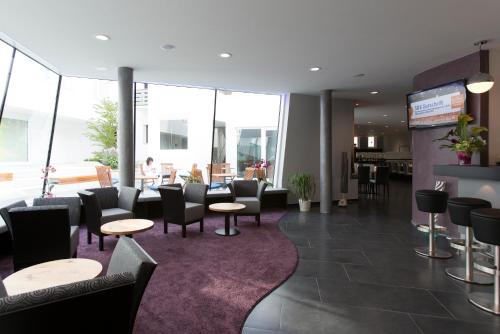 a waiting room with chairs and tables and windows at Hotel Barth in Kaiserslautern