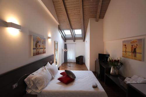 a bedroom with a bed with white sheets and red pillows at Albergo al Vecchio Tram in Udine