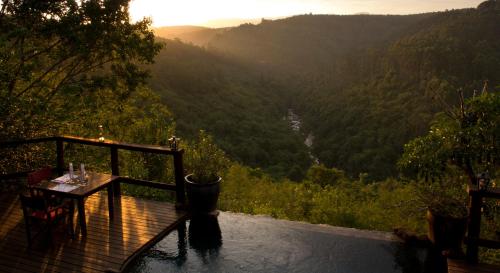 a table on a deck with a view of a valley at Tanamera Lodge in Hazyview