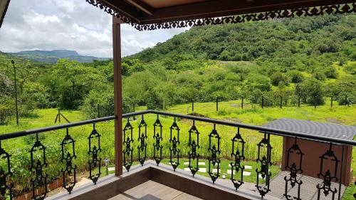 a balcony with a view of a lush green field at Nostravila in Lonavala