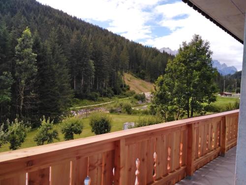 a balcony with a view of a field and trees at B&B DeBy & E-Bike Rental in San Nicolò di Comelico