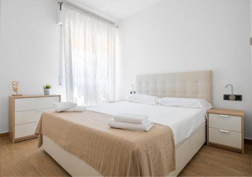 a white bedroom with a large bed with towels on it at Maka beach apartment v in Castelldefels