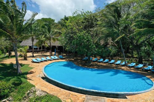 an empty swimming pool with lounge chairs and palm trees at Fumba Beach Lodge in Fumba