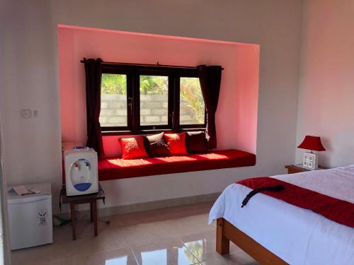 a bedroom with a red bench in front of a window at Wonder Dive Bali Tulamben Villa's in Tulamben