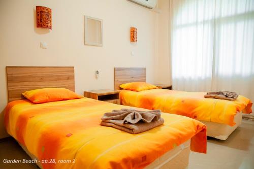 een slaapkamer met 2 bedden met oranje lakens bij DARI Apartments Garden Beach къмпинг ГРАДИНА in Chernomorets