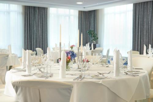 a dining room with white tables and white chairs at Dorint Hotel am Dom Erfurt in Erfurt