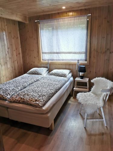 a bedroom with a bed and a window and a chair at Sunset puhkemaja in Kaigutsi
