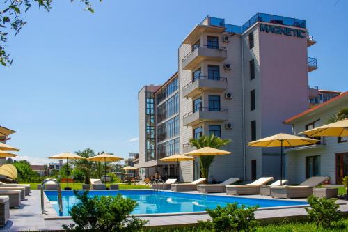 a pool with chairs and umbrellas next to a building at Magnetic Resort Ureki in Ureki