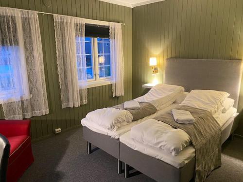 a bedroom with two beds and a red chair at Bergtun Hotell in Valle