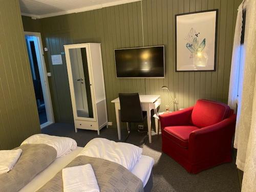 a room with two beds and a red chair and a desk at Bergtun Hotell in Valle