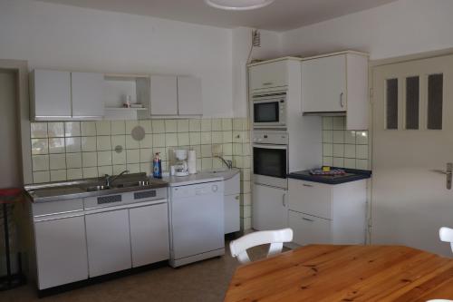 a kitchen with white cabinets and a wooden table at Haus-Dorfidyll in Spangenberg