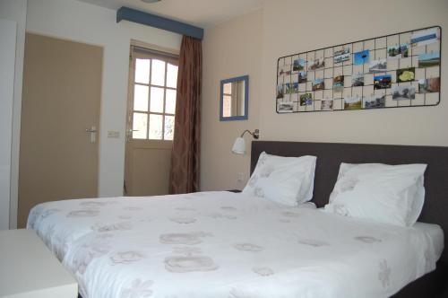 een slaapkamer met een groot bed met witte lakens bij B&B Gamerenwaard in Gameren
