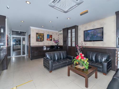ein Wohnzimmer mit schwarzen Ledersofas und einem Tisch in der Unterkunft Super OYO 89847 Switz Paradise Hotel in Kota Kinabalu