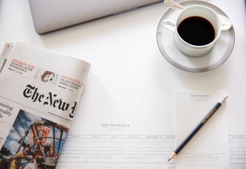 a newspaper and a cup of coffee and a pen at The Peninsula Shanghai in Shanghai