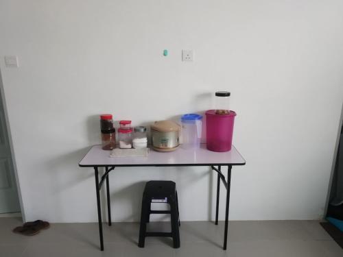 a small table with a stool next to a white wall at Fathullah's Homestay in Alor Setar