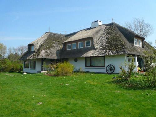 a house with a thatched roof on a green lawn at Teewelkenhues-Sonnenappartement in Archsum