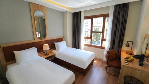 a hotel room with two beds and a mirror at Grand Sirkeci Hotel in Istanbul