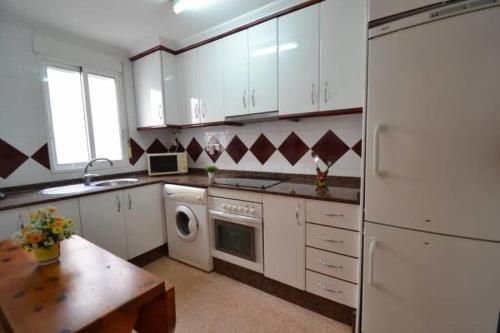 cocina con electrodomésticos blancos y mesa de madera en Nice Apartment Downtown - 2, en Torrevieja